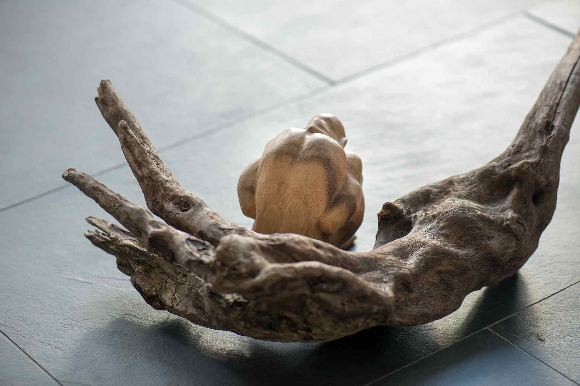 Traurige Holzskulptur vor Schwemmholz